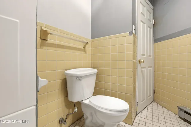 a view of a white house that has a small yard and large trees