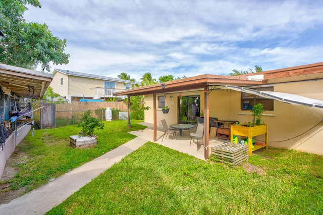 a view of a patio with table and chairs under an umbrella next to a yard