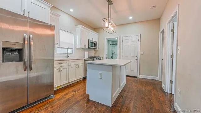 a kitchen with kitchen island a counter top space a sink stainless steel appliances and cabinets