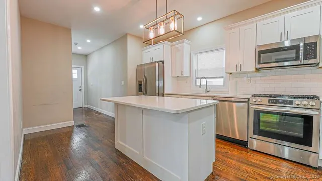 a kitchen with stainless steel appliances a sink cabinets and wooden floor