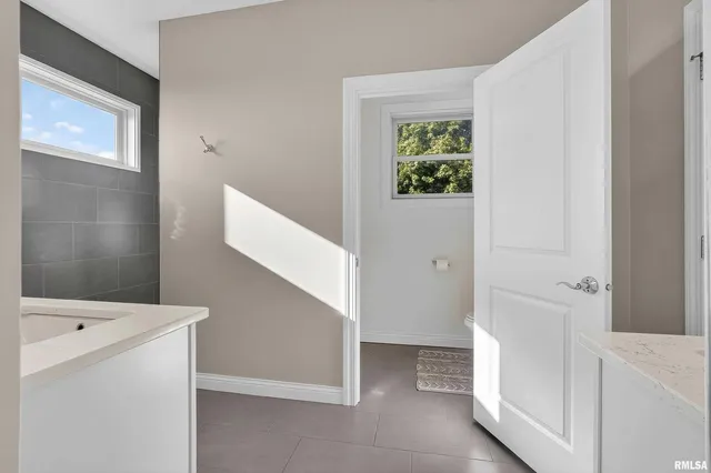 a spacious bathroom with a toilet a double vanity sink and a mirror