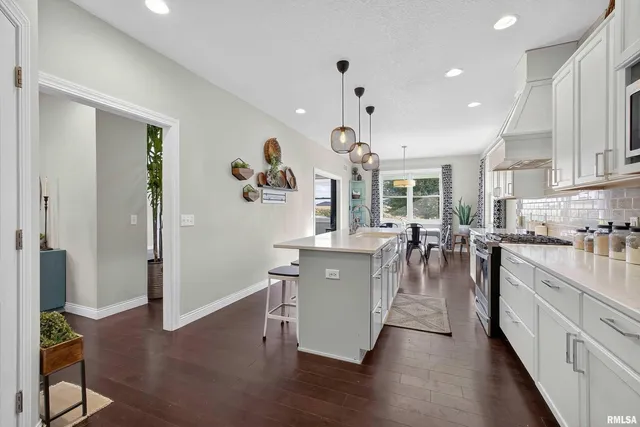 a living room with stainless steel appliances granite countertop furniture wooden floor and a view of kitchen