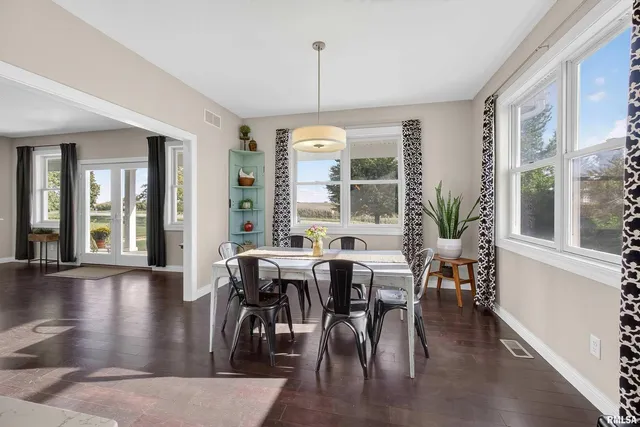 a dining room with wooden floor a chandelier a glass table and chairs