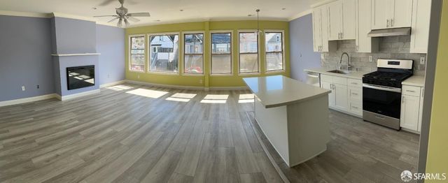 a open kitchen with granite countertop a stove top oven a sink and a wooden floor