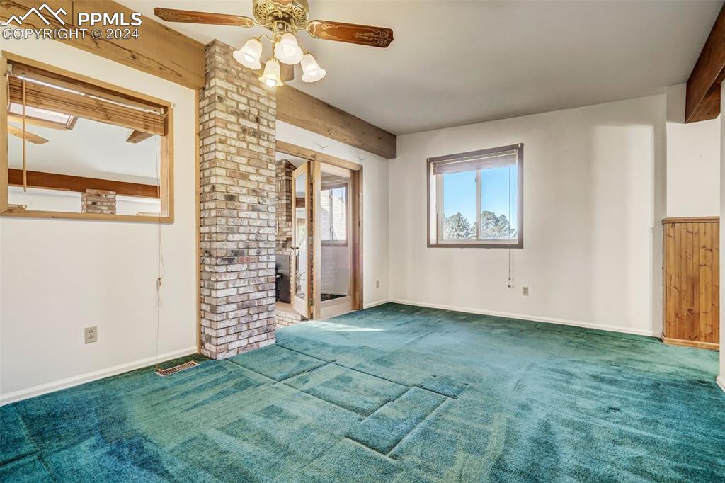 23555 Murphy Road Calhan, CO 80808 - Photo 34 of 49 Unfurnished living room featuring beam ceiling, carpet, and ceiling fan