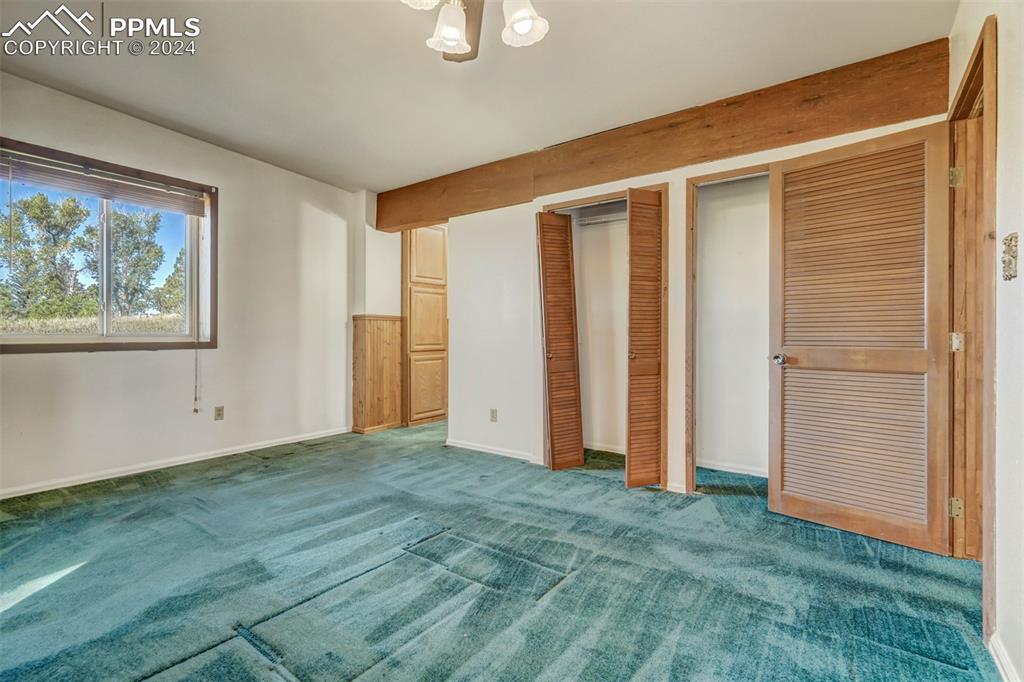 23555 Murphy Road Calhan, CO 80808 - Photo 35 of 49 Unfurnished bedroom featuring carpet floors, an inviting chandelier, and two closets