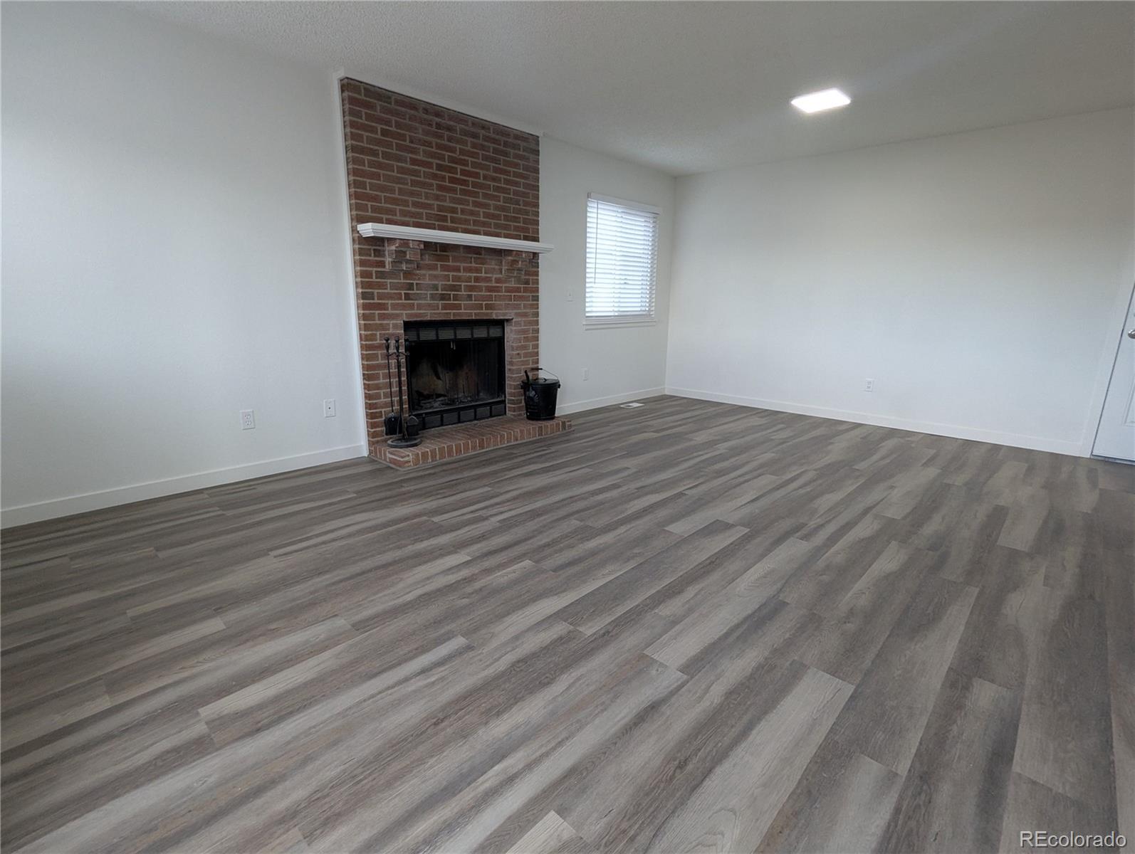 444 Spring Grove Avenue Highlands Ranch, CO 80126 - Photo 14 of 21 a view of an empty room with wooden floor fireplace and a window