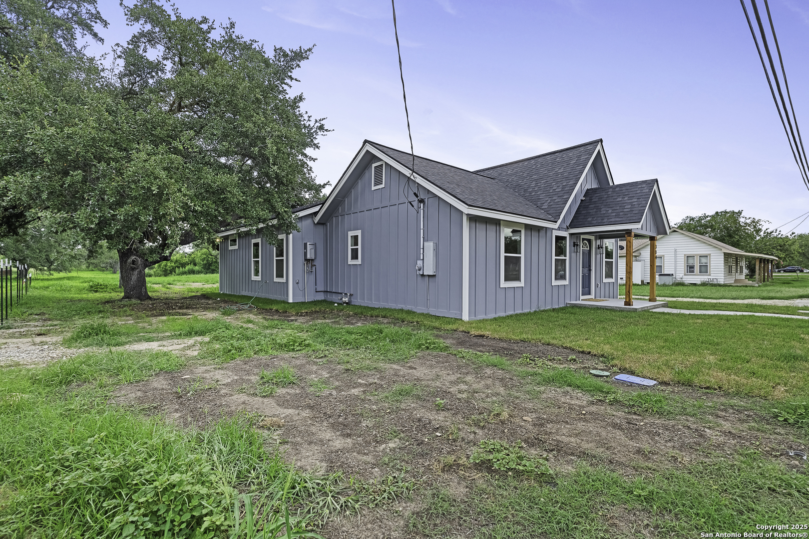 a view of a house with a big yard plants and large trees