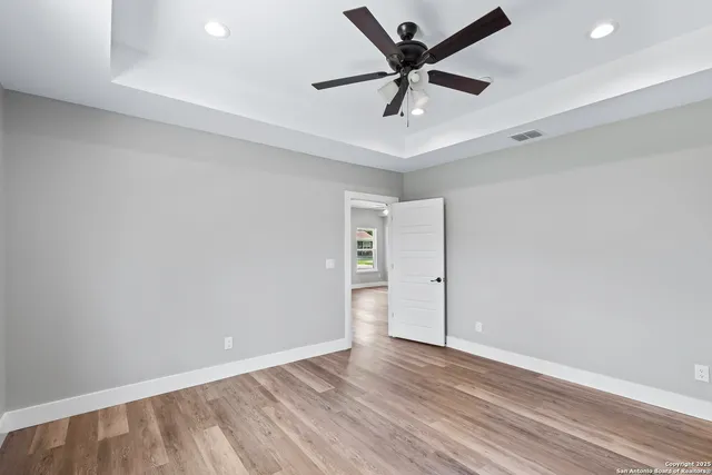 an empty room with wooden floor and ceiling fan