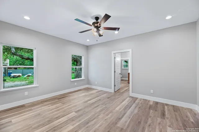 a view of an empty room with wooden floor and a window