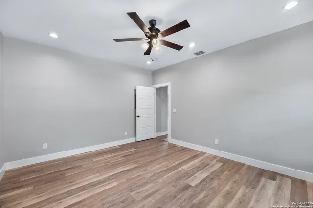 an empty room with wooden floor and ceiling fan