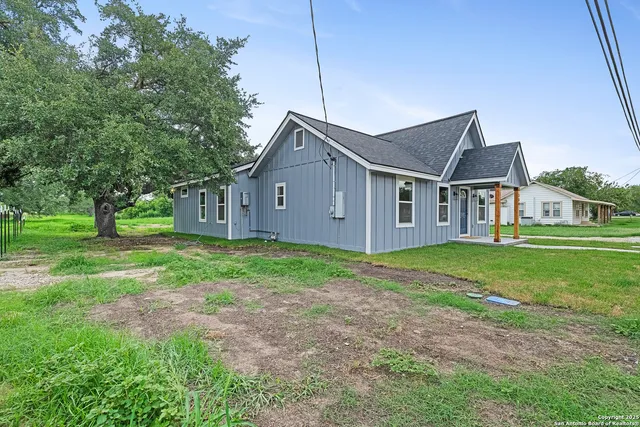 a view of a house with a big yard plants and large trees