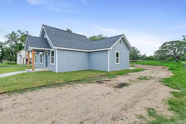 a backyard of a house with plants and large tree