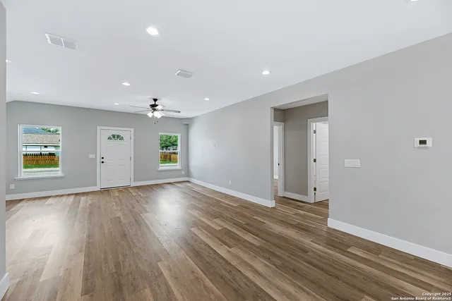 an empty room with wooden floor and windows