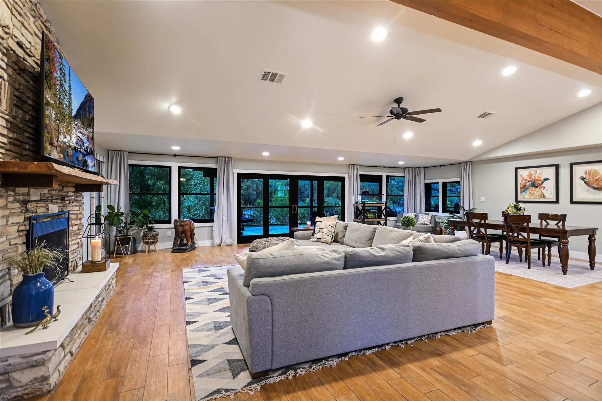 2411 Spoke Hollow Road Wimberley, TX 78676 - Photo 6 of 37 An inviting great room with wood flooring and a stone fireplace offers serene outdoor views.