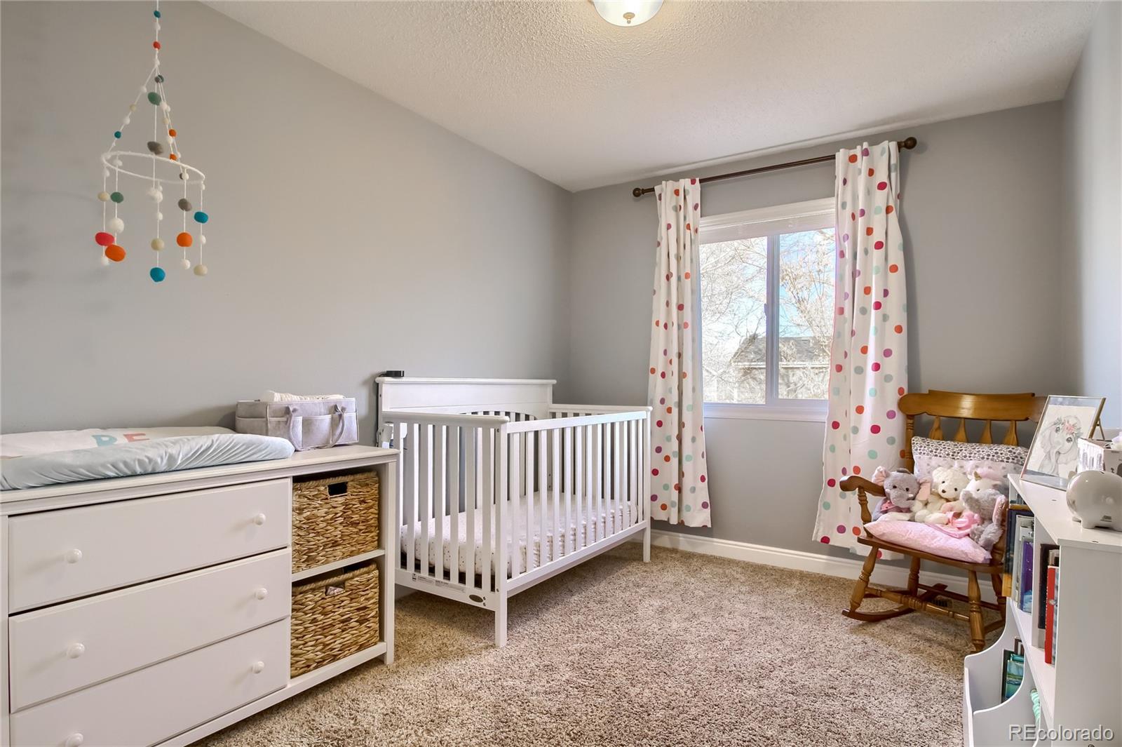 1031 Timbervale Trail Highlands Ranch, CO 80129 - Photo 20 of 34 a bedroom with a baby bed a couch and a window