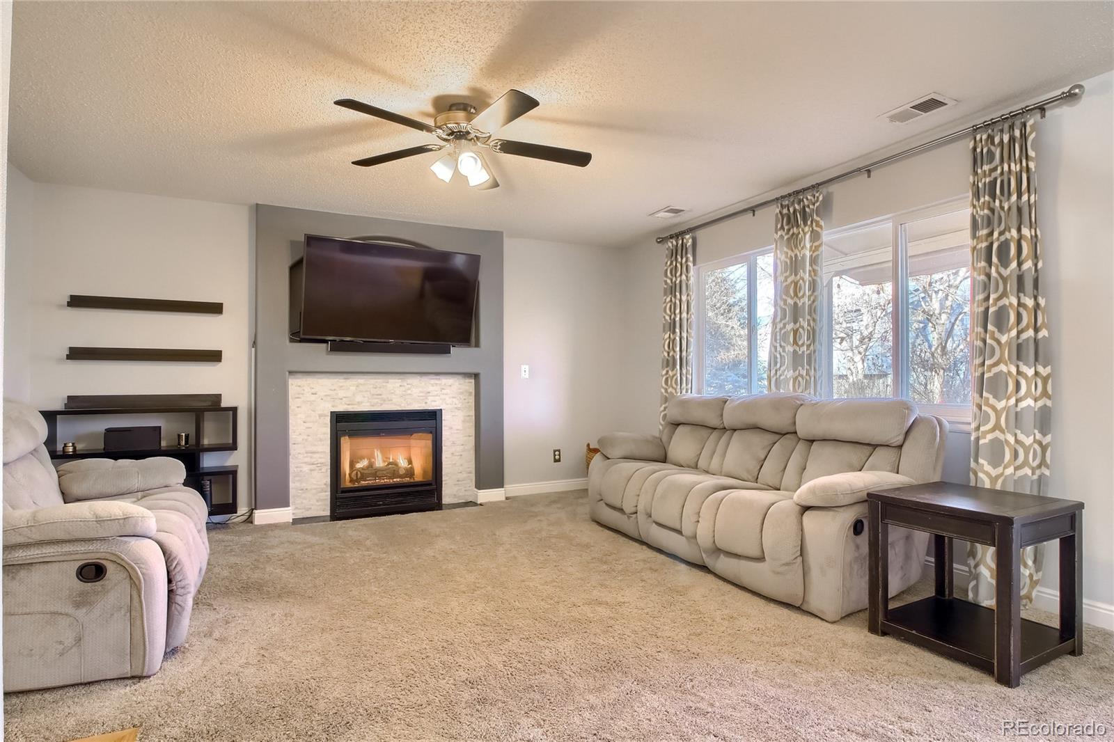 1031 Timbervale Trail Highlands Ranch, CO 80129 - Photo 5 of 34 a living room with furniture a fireplace and a flat screen tv