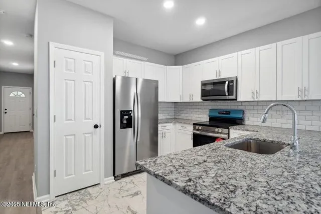 a kitchen with stainless steel appliances granite countertop a refrigerator stove and sink
