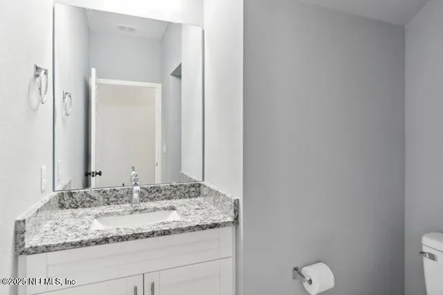 a bathroom with a granite countertop sink and a mirror