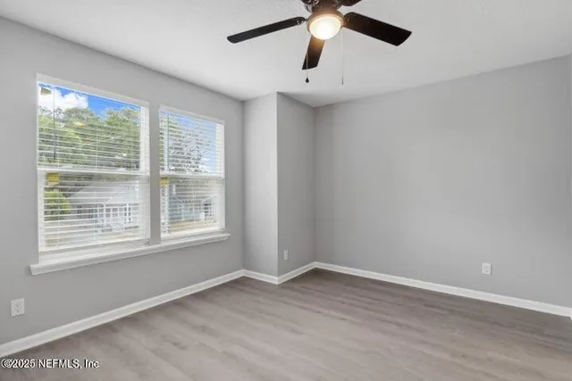 an empty room with a window and a fan