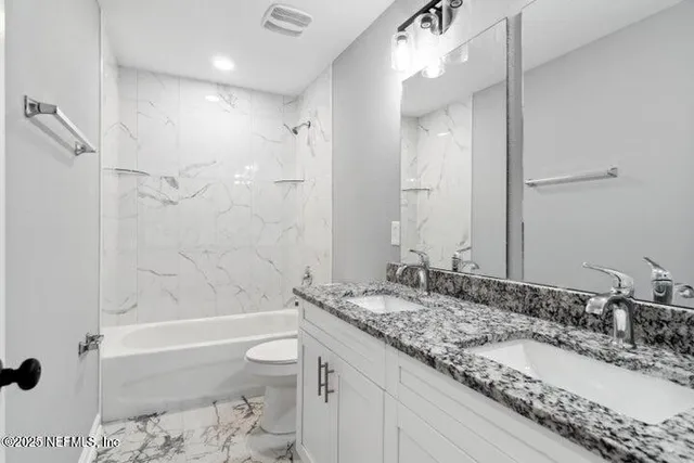 a bathroom with a granite countertop sink a toilet and shower