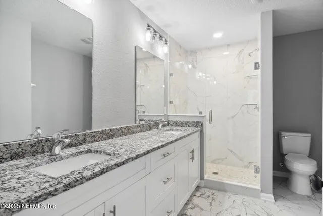 a bathroom with a granite countertop sink mirror vanity and toilet