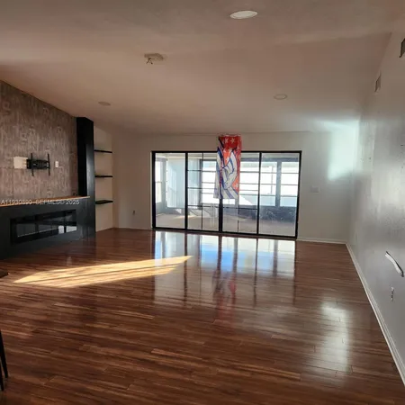 a view of empty room with wooden floor and floor to ceiling window