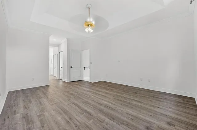 an empty room with wooden floor fan and windows