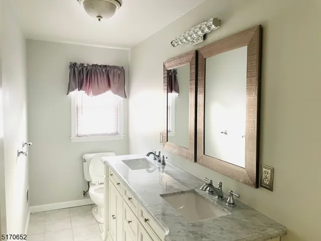 a bathroom with a granite countertop sink toilet and mirror