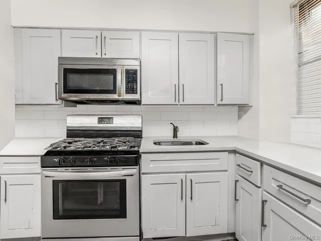 a kitchen with white cabinets stainless steel appliances and a sink