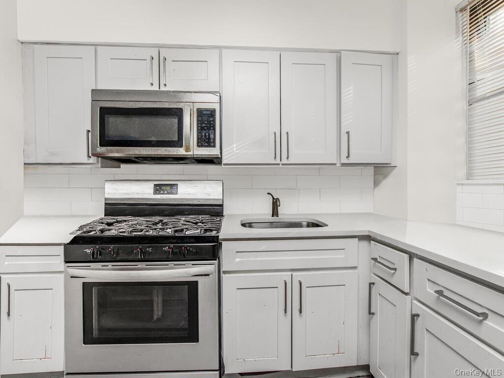 829 Adee Avenue, Unit 2L Bronx, NY 10467 - Photo 6 of 9 a kitchen with white cabinets stainless steel appliances and a sink