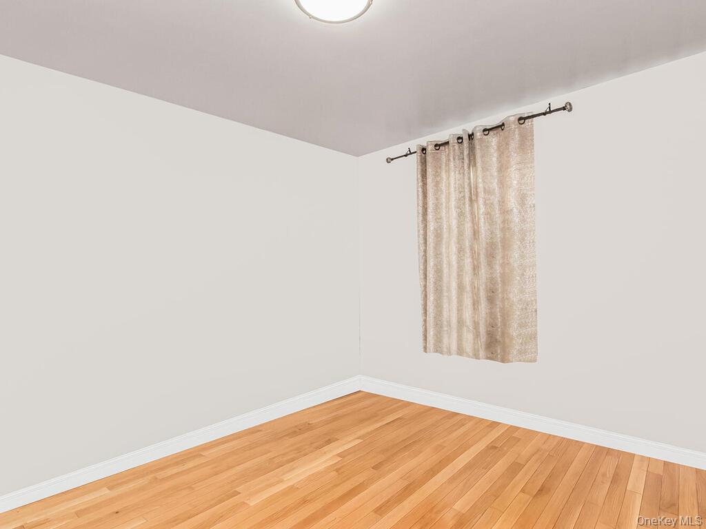 829 Adee Avenue, Unit 2L Bronx, NY 10467 - Photo 7 of 9 a view of an empty room with wooden floor and a window