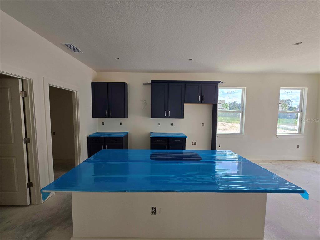 3844 Daybreak Run Loop Spring Hill, FL 34609 - Photo 3 of 11 a kitchen with stainless steel appliances granite countertop a refrigerator a stove top oven a sink dishwasher and wooden cabinets with wooden floor