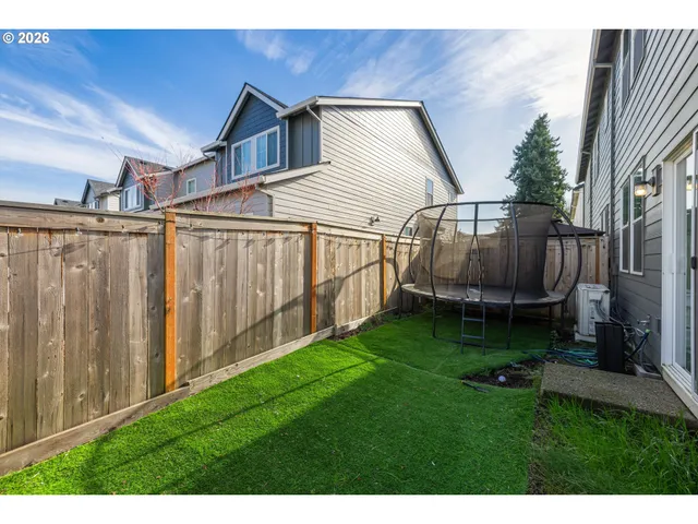 a backyard of a house with lots of green space and wooden fence