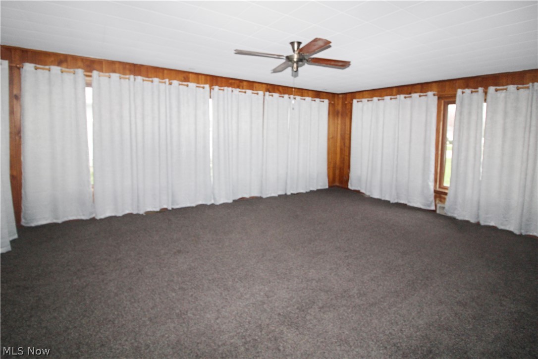 1036 West Fremont Road Port Clinton, OH 43452 - Photo 3 of 32 Empty room with dark carpet and ceiling fan