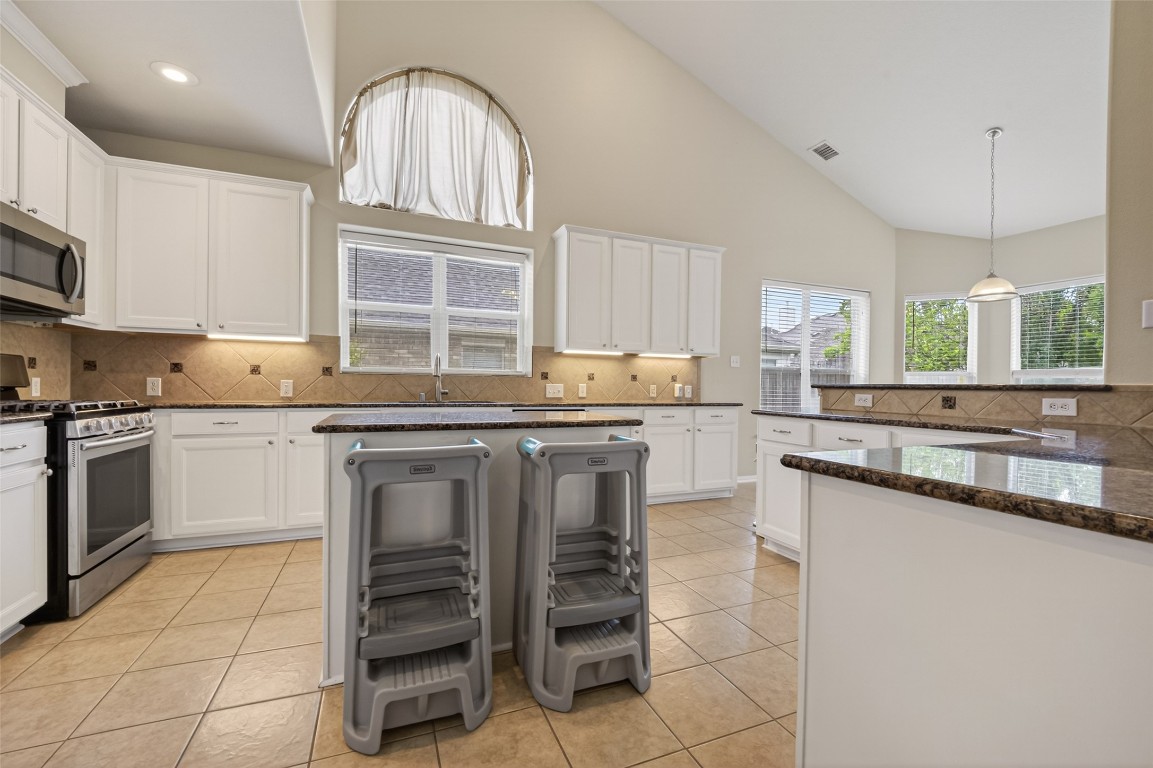 3219 Legends Mist Drive Spring, TX 77386 - Photo 18 of 50 a kitchen with kitchen island granite countertop a stove sink and cabinets