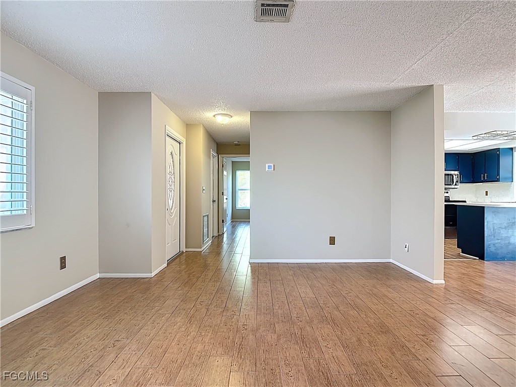 5946 Stringfellow Road St. James City, FL 33956 - Photo 11 of 50 a view of an empty room with wooden floor and a window