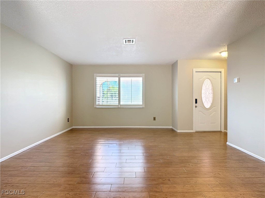 5946 Stringfellow Road St. James City, FL 33956 - Photo 12 of 50 an empty room with wooden floor and windows