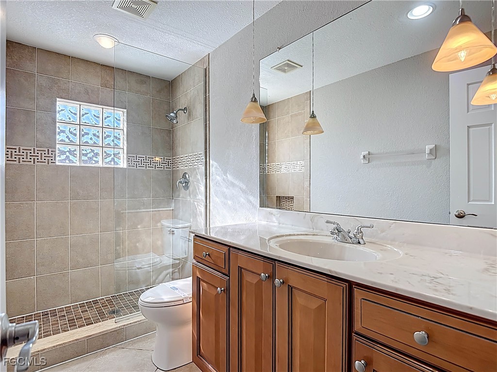 5946 Stringfellow Road St. James City, FL 33956 - Photo 35 of 50 a bathroom with a sink a toilet a mirror and shower