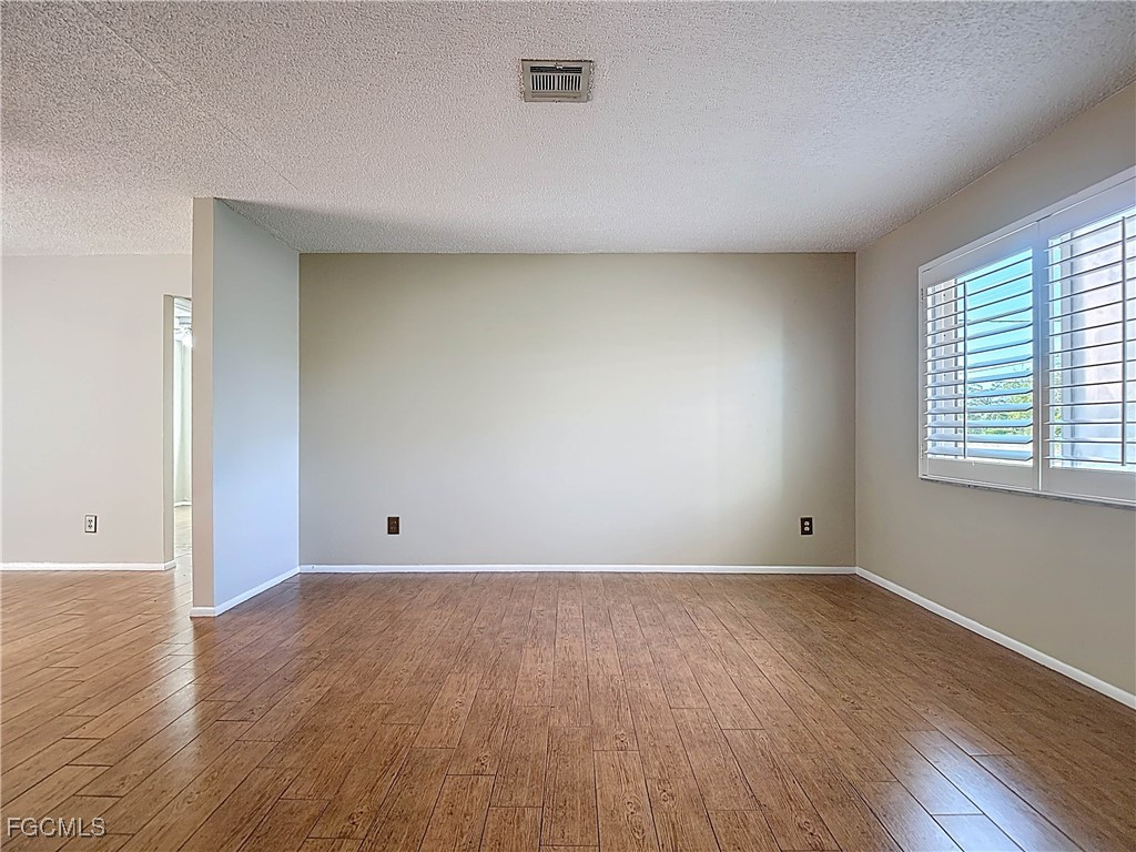 5946 Stringfellow Road St. James City, FL 33956 - Photo 9 of 50 a view of an empty room with wooden floor and a window
