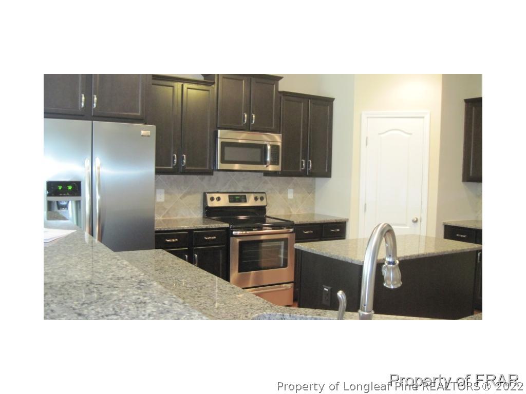 775 Sun Road Aberdeen, NC 28315 - Photo 7 of 17 a kitchen with kitchen island granite countertop a stove a refrigerator a sink a microwave and island