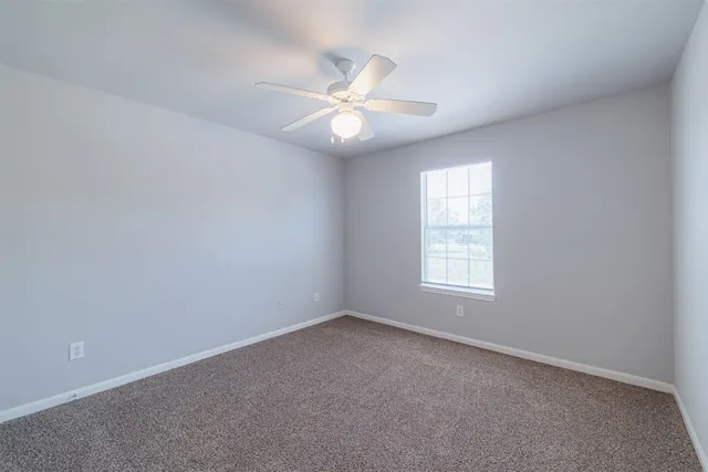 an empty room with a window and a fan