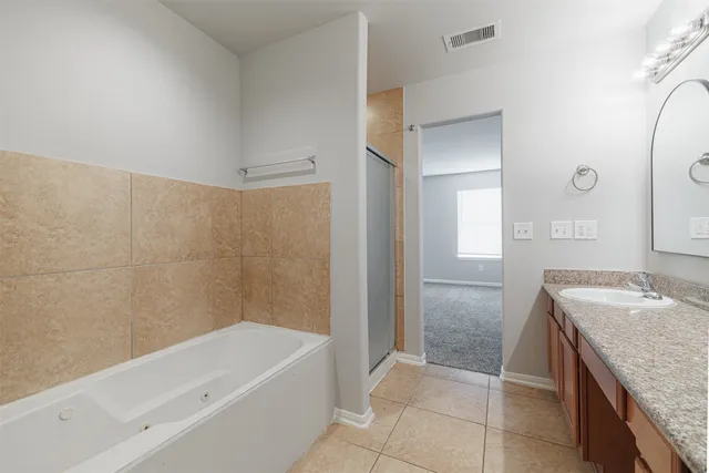 a bathroom with a granite countertop sink a mirror and a bathtub