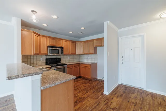 a kitchen with granite countertop a stove top oven a sink a counter space and cabinets