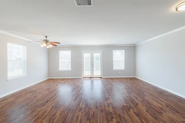 a view of empty room with wooden floor and fan