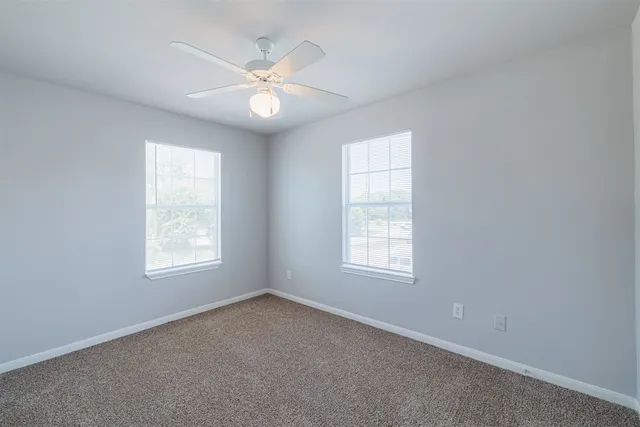 an empty room with windows and fan