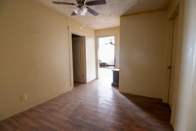 a view of a room with a chandelier fan and wooden floor