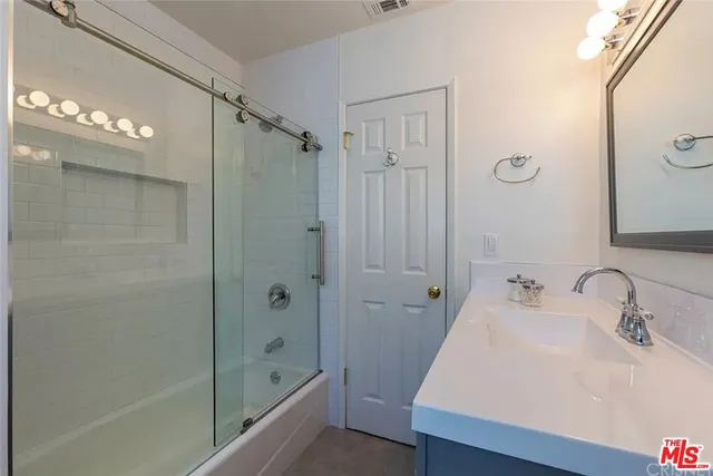 a bathroom with a sink shower and a mirror