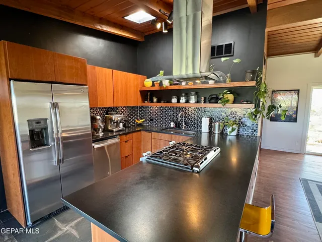 a kitchen with stainless steel appliances a refrigerator a stove a sink and a dining table with wooden floor