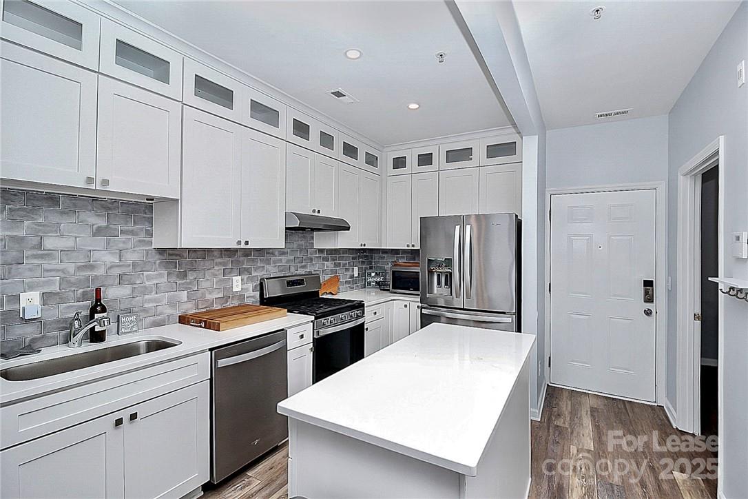 2625 East 5th Street, Unit A Charlotte, NC 28204 - Photo 12 of 24 a kitchen with kitchen island a refrigerator sink and white cabinets